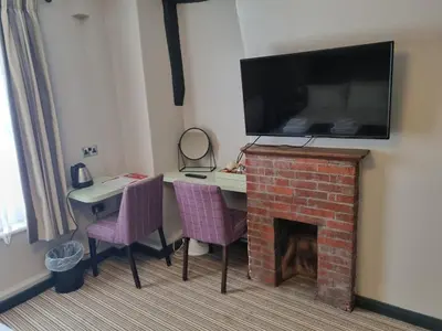 a room with a table and a fireplace with a tv above it at The Red Lion Hotel in Cambridge