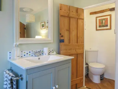 a bathroom with a sink and a toilet and a mirror at Ivy Cottage in Aldeburgh