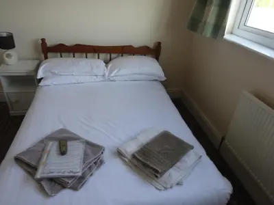 a bed with white sheets and towels and a window at Lantern House in Cambridge