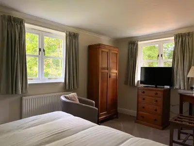 a bedroom with a bed and a tv and windows at The Cottage Guest House in Bishops Stortford