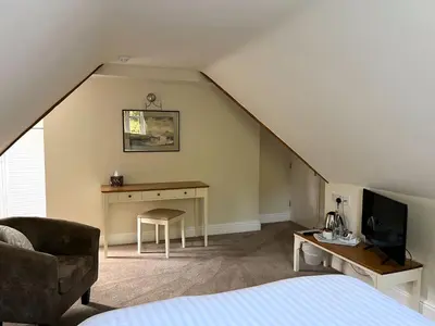 a room with a bed and a desk in a attic at The Cottage Guest House in Bishops Stortford