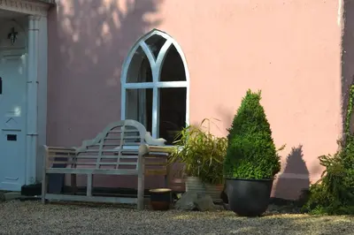 a bench in front of a pink building with a window at The Cottage Guest House in Bishops Stortford