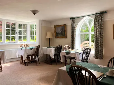 a dining room with two tables and a window at The Cottage Guest House in Bishops Stortford