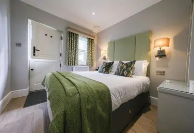 a bedroom with a large bed with a green blanket on it at Mulberry House in Ongar