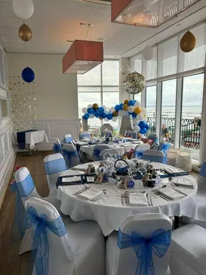 a dining room with tables and chairs with blue bows at The Palace Hotel in Southend-on-Sea
