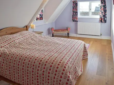 a bedroom with a bed with a red comforter at Granary Cottage in Bentley