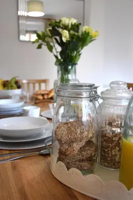 a table with jars of food and a vase of flowers at Friarscroft Lodge Holiday Home in Wymondham