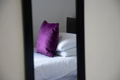 a mirror with a purple pillow on top of a bed at Friarscroft Lodge Holiday Home in Wymondham