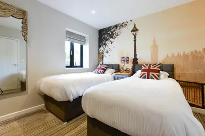 a bedroom with two beds and a wall with a mural at The Bell Inn in Newmarket