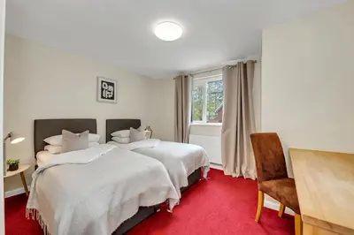 a bedroom with two beds and a red carpet at The Cambridgeshire in Newmarket