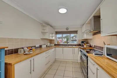 a kitchen with white cabinets and a large window at The Cambridgeshire in Newmarket