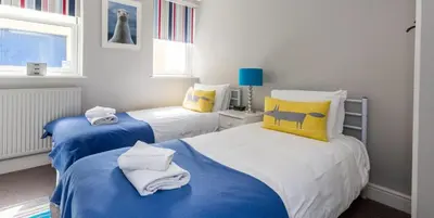two beds in a room with blue and yellow at Waterfront Cottage in Aldeburgh