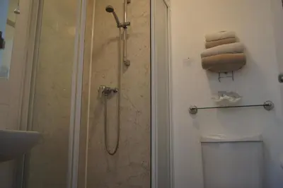a bathroom with a shower with a toilet and towels at Alder Lodge in Cambridge