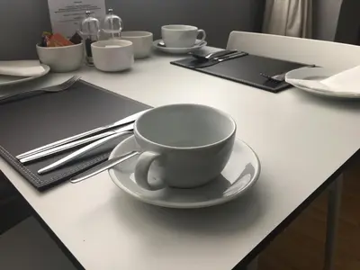 a white coffee cup on a plate on a table at Alder Lodge in Cambridge