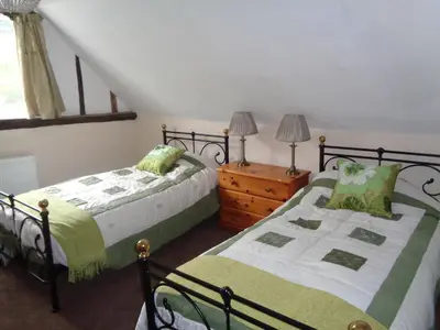 a bedroom with two beds and a wooden dresser at Minsmere Cottage in Yoxford