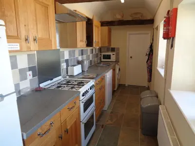 a kitchen with wooden cabinets and a stove top oven at Minsmere Cottage in Yoxford