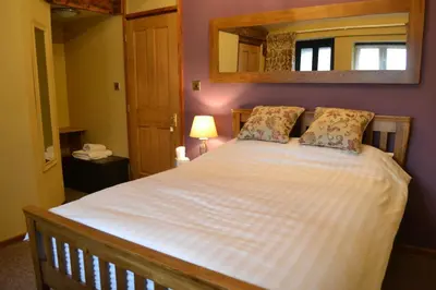 a bedroom with a bed with a mirror on the wall at Old Field Barn Luxury B&B in Attleborough