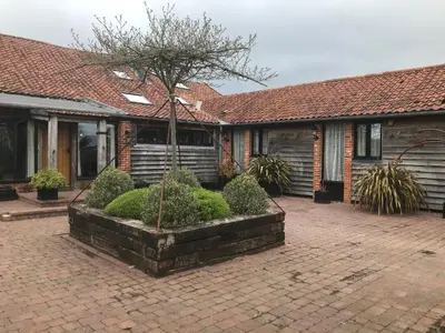 a house with a courtyard with a tree in it at Old Field Barn Luxury B&B in Attleborough