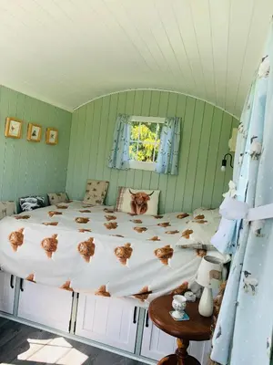 a bedroom with a large bed in a green room at Bells Meadow Shepherds Hut in Kings Lynn
