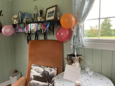 a table with balloons and a table with a chair at Bells Meadow Shepherds Hut in Kings Lynn