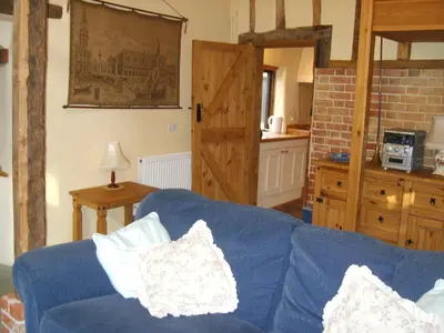 a living room with a blue couch and a kitchen at Granary Cottage in Hardwick