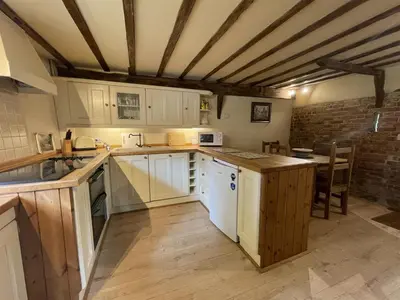 a kitchen with white cabinets and a table in it at Granary Cottage in Hardwick