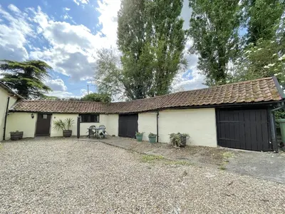 a house with two garage doors and a gravel driveway at Granary Cottage in Hardwick