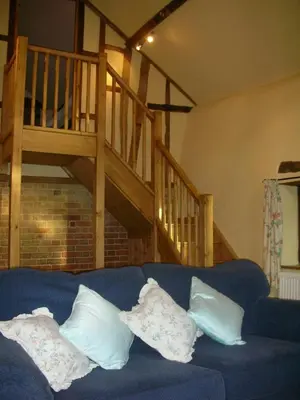 a blue couch with four pillows on it in a living room at Granary Cottage in Hardwick