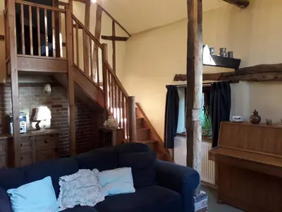 a living room with a blue couch and a staircase at Granary Cottage in Hardwick