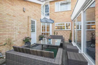 a patio with two wicker chairs and a glass table at The Holly Tree in Cambridge