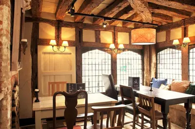 a dining room with a table and chairs and windows at The Cross Keys in Saffron Walden
