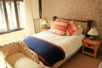 a bedroom with a bed and a chair and a window at The Cross Keys in Saffron Walden