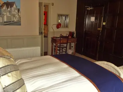 a bedroom with a large bed and a table at The Cross Keys in Saffron Walden