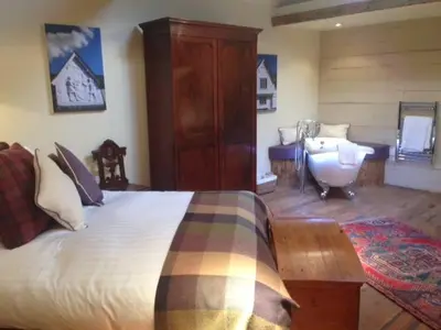 a bedroom with a bed and a tub and a sink at The Cross Keys in Saffron Walden