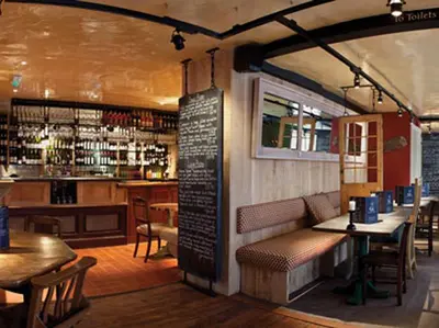 a restaurant with tables and chairs and a bar at The Cross Keys in Saffron Walden