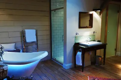 a bathroom with a tub and a sink and a mirror at The Cross Keys in Saffron Walden