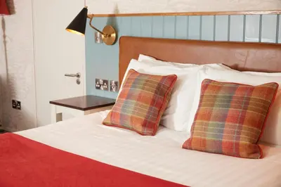 a bed with two plaid pillows on it at Feathers by Chef & Brewer Collection in Wadesmill