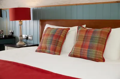 a bed with two plaid pillows and a red lamp at Feathers by Chef & Brewer Collection in Wadesmill