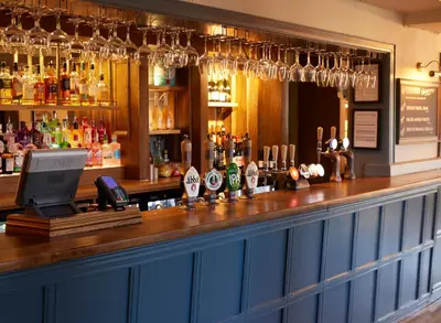 a bar with a counter with a phone and alcohol at Feathers by Chef & Brewer Collection in Wadesmill