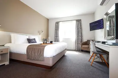 a hotel room with a bed and a desk and a computer at All Saints Resort in Bury Saint Edmunds