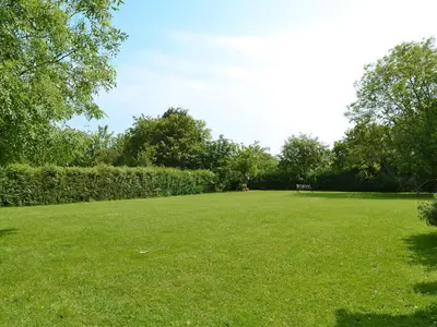 a large grassy field with a bench in the distance at Hillcroft in Cold Norton