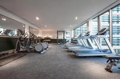 a gym with a row of treadmills and machines at Clayton Hotel Cambridge in Cambridge