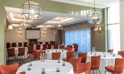 a conference room with tables and chairs and a screen at Clayton Hotel Cambridge in Cambridge