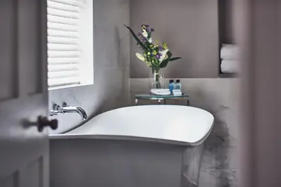 a bathroom with a white sink and a vase of flowers at Marquis Suffolk in Ipswich