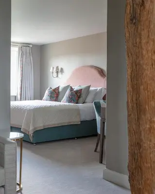 a bedroom with a large bed with a pink headboard at Marquis Suffolk in Ipswich