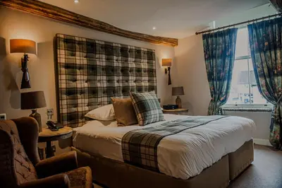 a bedroom with a bed and a chair and a window at The White Hart Hotel in Hingham