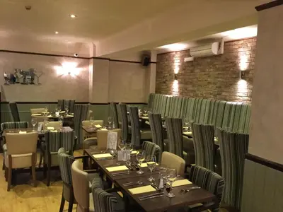 a restaurant with tables and chairs and a brick wall at Rettendon Lodge in Battlesbridge