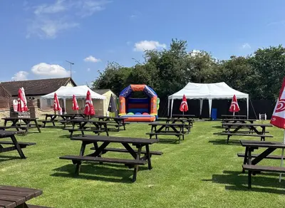 a group of picnic tables in a field with tents at Rettendon Lodge in Battlesbridge