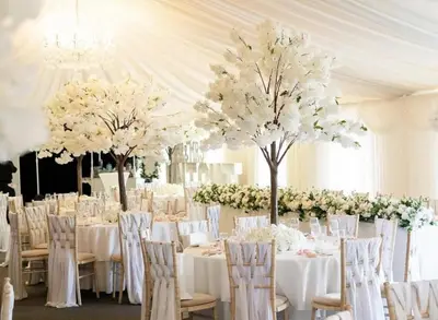 a banquet hall with white tables and chairs and trees at Rettendon Lodge in Battlesbridge