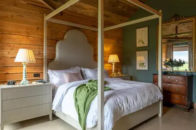 a bedroom with a canopy bed and a wooden wall at Cambridge Country Cottages in Cambridge